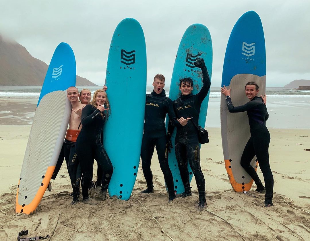 Folkehøgskolelever med surfebrett på strand